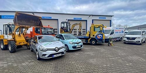 Hof der Kfz-Service Park GmbH in Naunhof: Radlader, Minibagger, Kipper, Abschleppfahrzeug und Mietwagen vor den Werkstatttoren